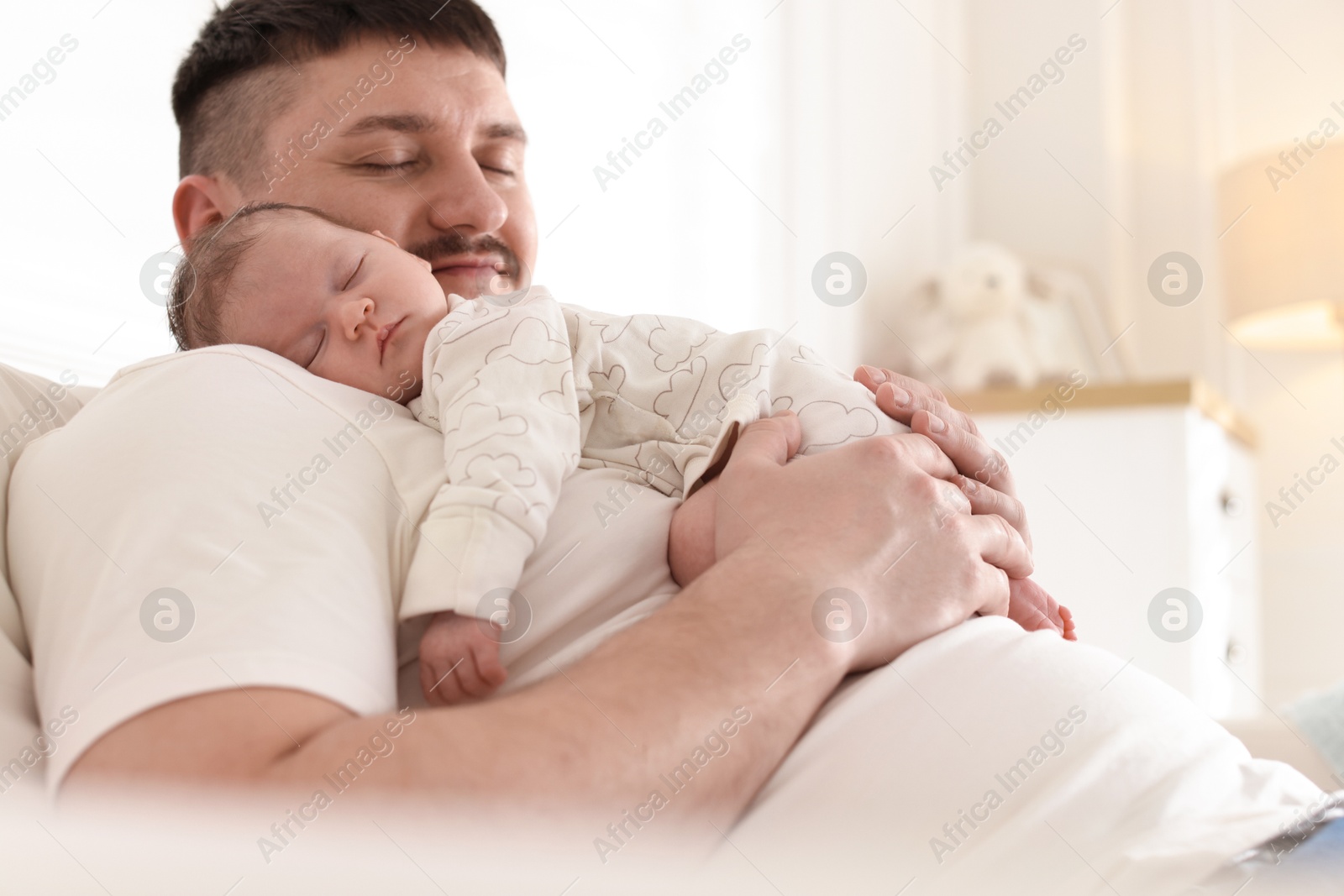 Father with his cute newborn baby indoors Photo of Father with his cute newborn baby indoors