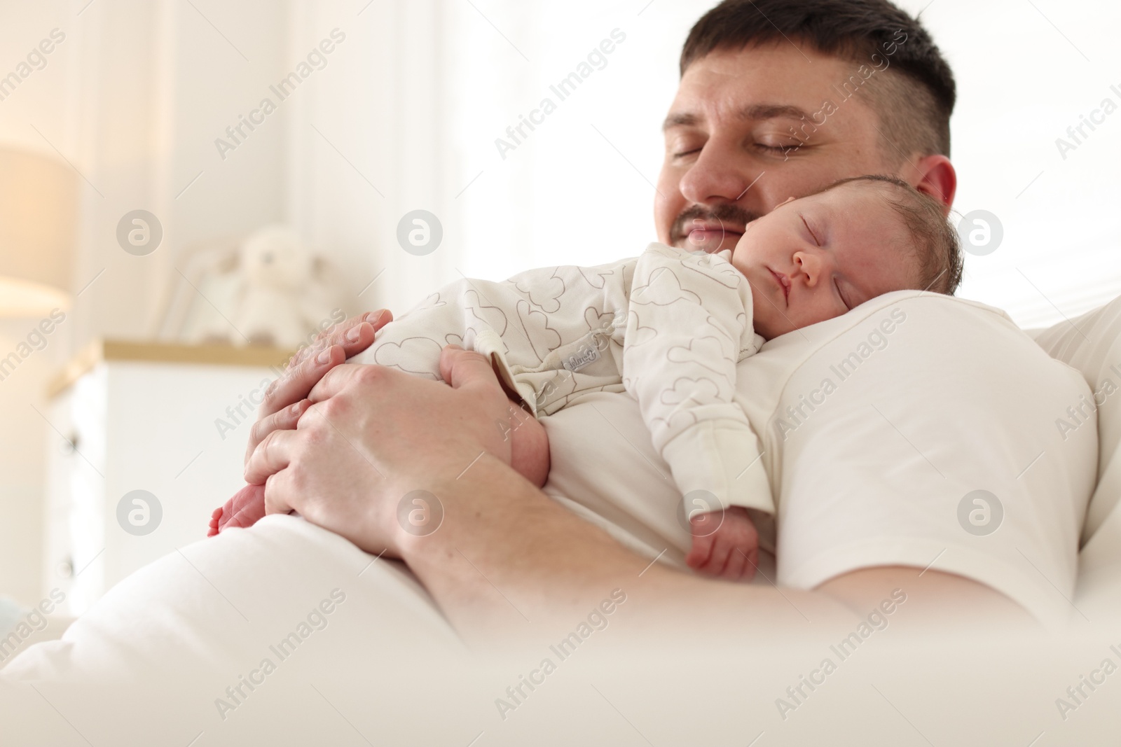 Father with his cute newborn baby indoors Photo of Father with his cute newborn baby indoors
