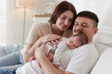 Photo of Happy parents with their cute newborn baby on sofa indoors
