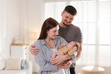 Photo of Happy parents with their cute newborn baby indoors