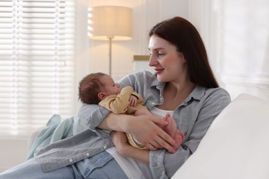 Photo of Mother with her cute newborn baby on sofa indoors