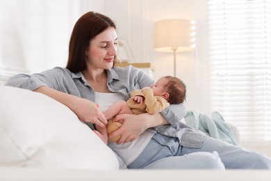Photo of Mother with her cute newborn baby on sofa indoors