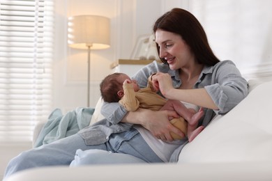 Photo of Mother with her cute newborn baby on sofa indoors