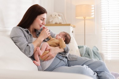 Photo of Mother with her cute newborn baby on sofa indoors
