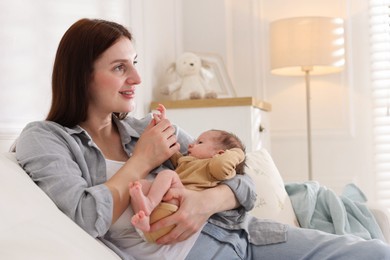 Photo of Mother with her cute newborn baby on sofa indoors