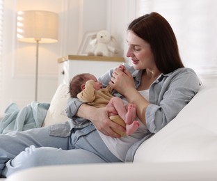 Photo of Mother with her cute newborn baby on sofa indoors