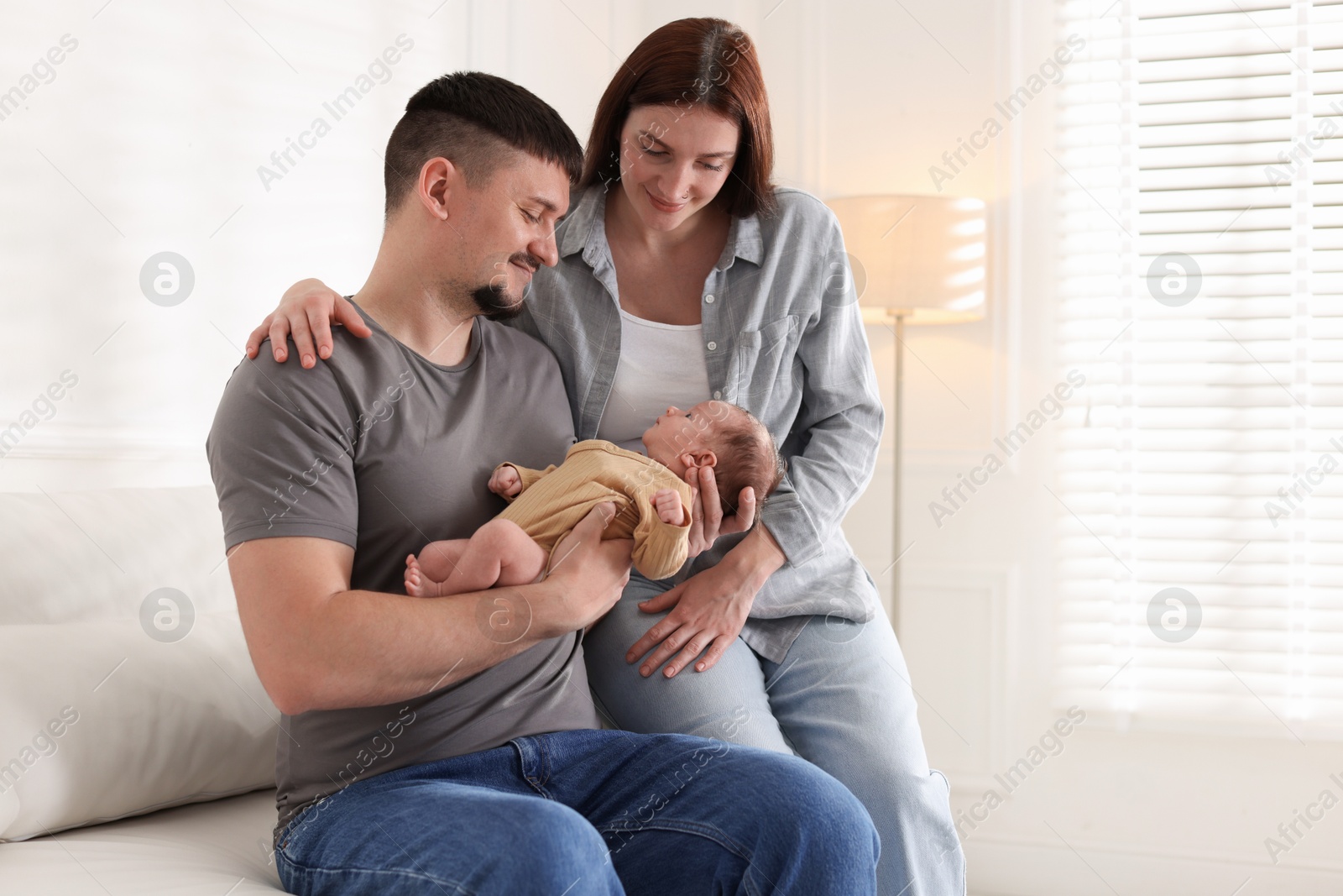 Happy parents with their cute newborn baby indoors, space for text Photo of Happy parents with their cute newborn baby indoors, space for text
