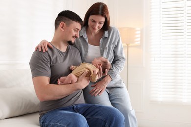 Photo of Happy parents with their cute newborn baby indoors, space for text