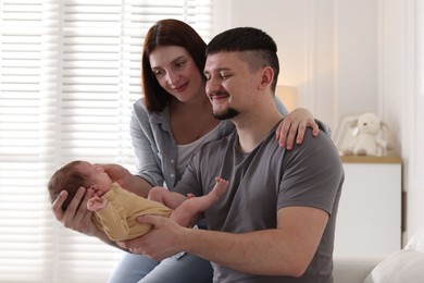 Photo of Happy parents with their cute newborn baby indoors