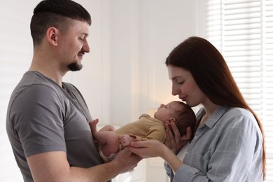 Photo of Happy parents with their cute newborn baby indoors