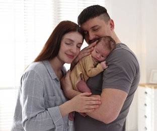 Photo of Happy parents with their cute newborn baby indoors