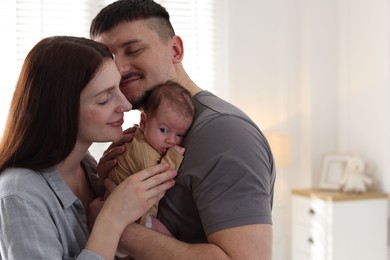 Photo of Happy parents with their cute newborn baby indoors, space for text