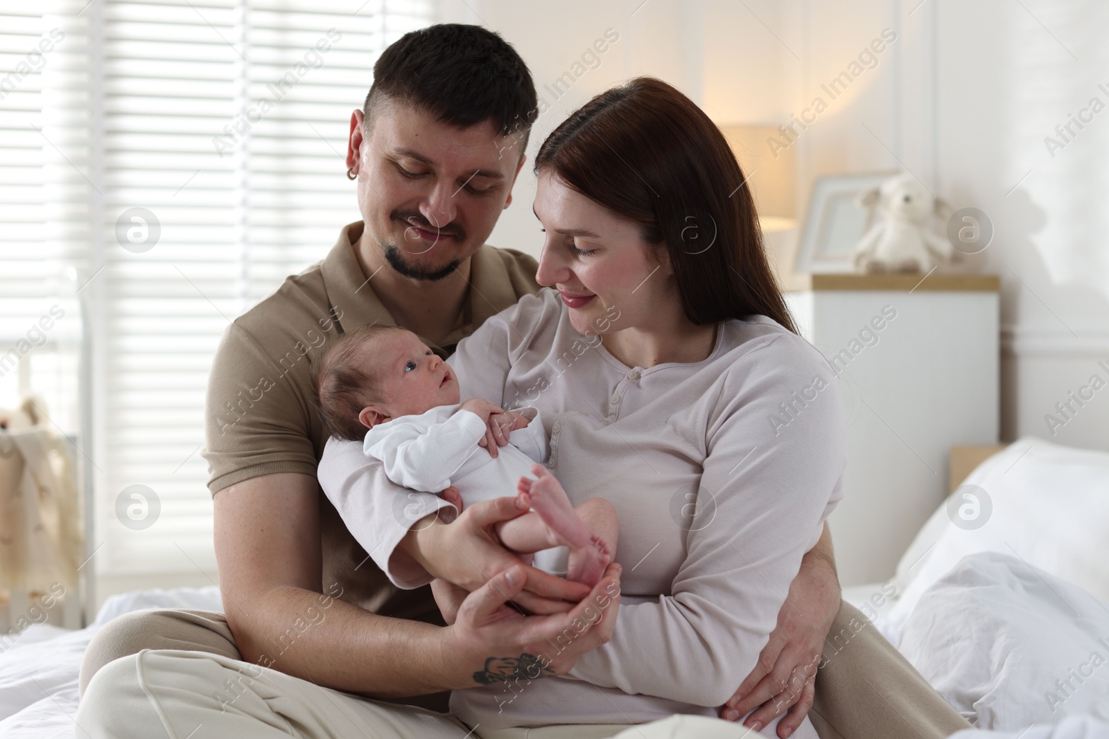 Happy parents with their cute newborn baby on bed indoors Photo of Happy parents with their cute newborn baby on bed indoors