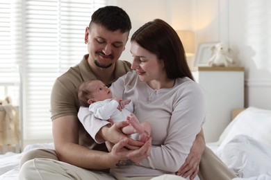 Photo of Happy parents with their cute newborn baby on bed indoors