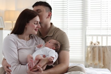 Photo of Happy parents with their cute newborn baby on bed indoors, space for text