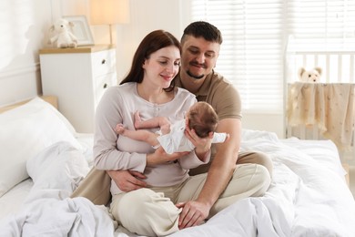 Photo of Happy parents with their cute newborn baby on bed indoors