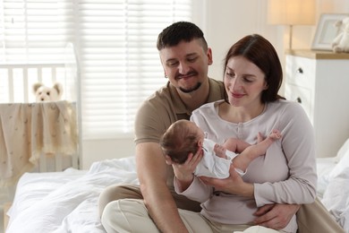 Photo of Happy parents with their cute newborn baby on bed indoors, space for text