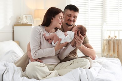 Photo of Happy parents with their cute newborn baby on bed indoors