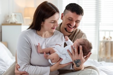 Photo of Happy parents with their cute newborn baby on bed indoors