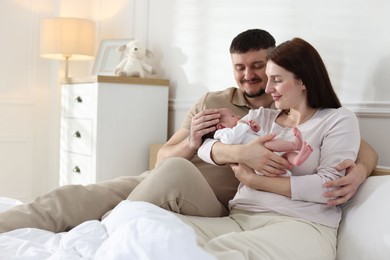 Photo of Happy parents with their cute newborn baby on bed indoors