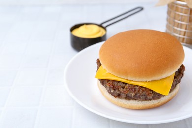 Photo of Cheeseburger with tasty patty and sauce on white tiled table, closeup. Space for text