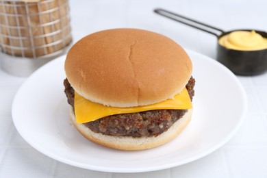 Photo of Cheeseburger with tasty patty and sauce on white table, closeup