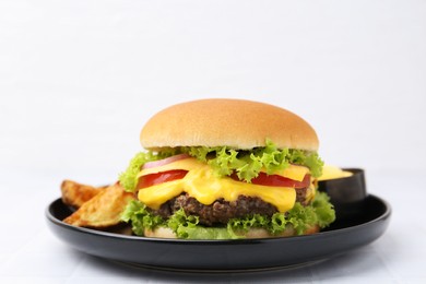 Photo of Tasty cheeseburger with sauce and potato wedges on white table, closeup