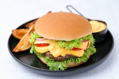 Photo of Tasty cheeseburger with sauce and potato wedges on white table, closeup