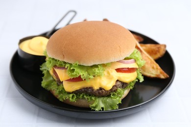 Photo of Tasty cheeseburger with sauce and potato wedges on white table, closeup