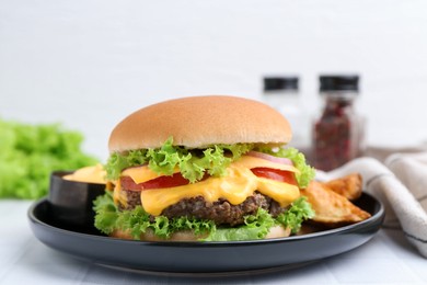 Photo of Tasty cheeseburger with sauce and potato wedges on white table, closeup