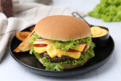 Photo of Tasty cheeseburger with sauce and potato wedges on white table, closeup