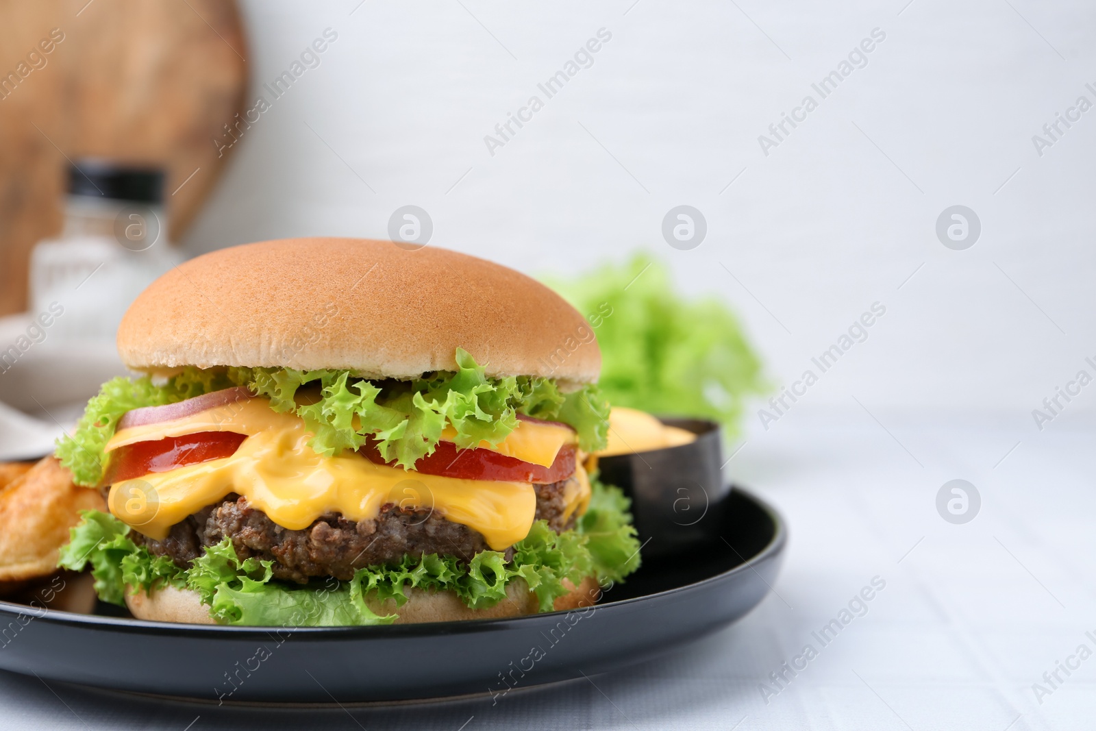 Tasty cheeseburger with sauce on white table, closeup. Space for text Photo of Tasty cheeseburger with sauce on white table, closeup. Space for text
