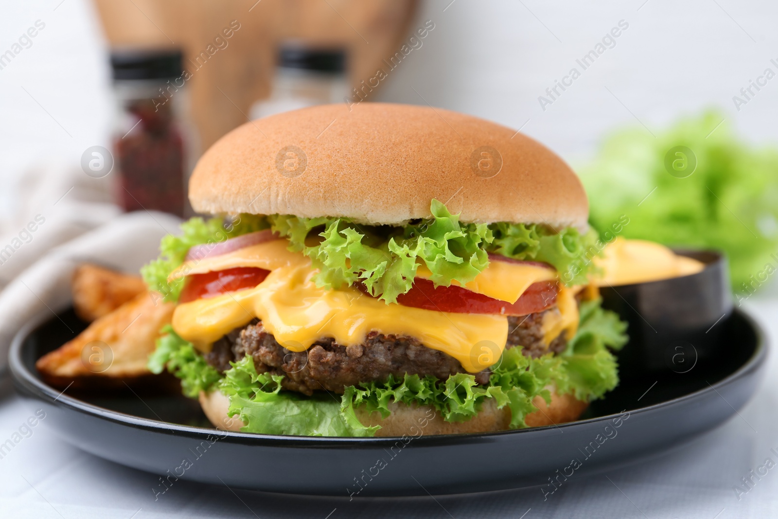 Tasty cheeseburger with sauce on white table, closeup Photo of Tasty cheeseburger with sauce on white table, closeup