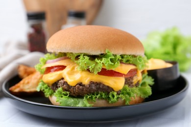 Photo of Tasty cheeseburger with sauce on white table, closeup