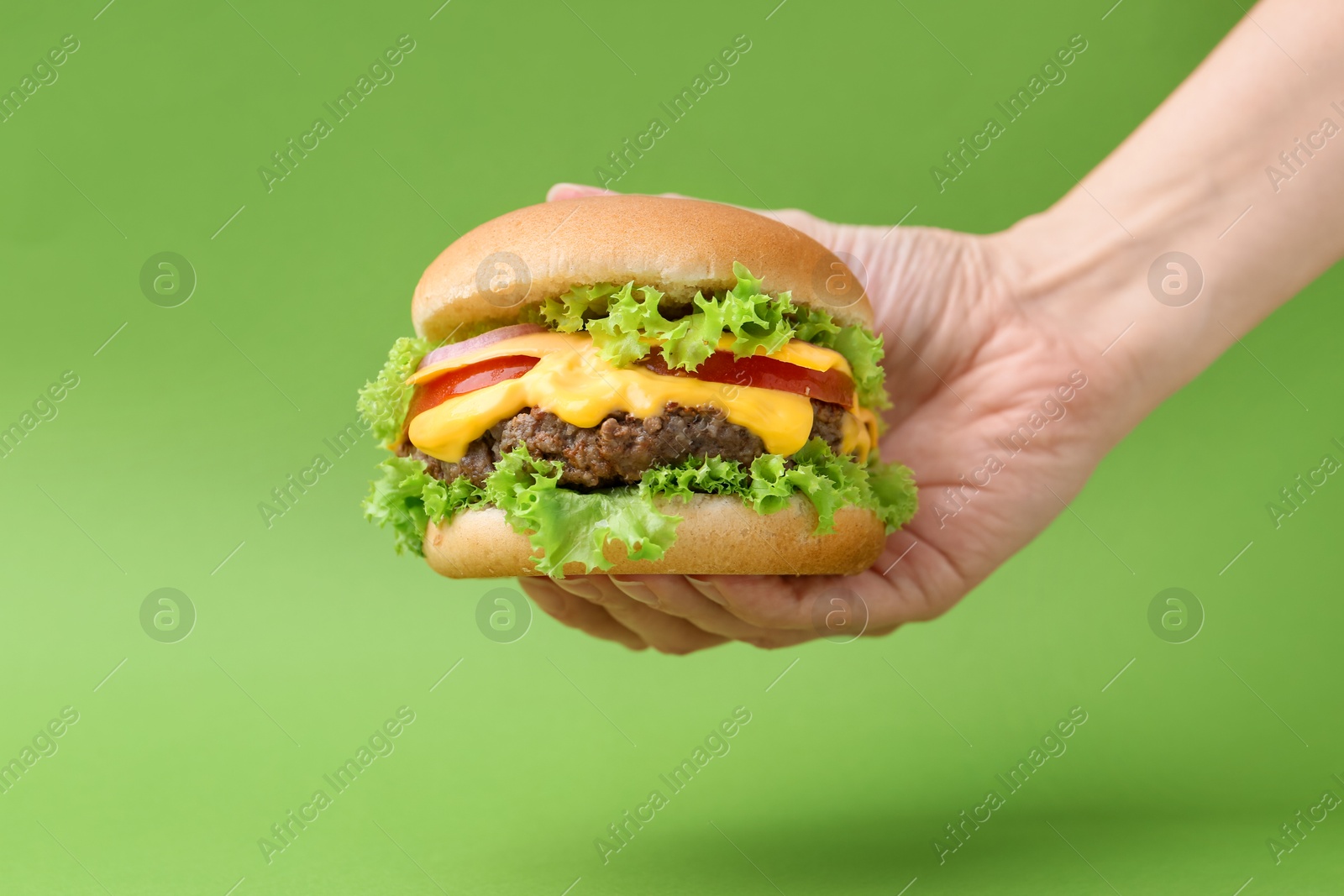 Woman with tasty cheeseburger on green background, closeup Photo of Woman with tasty cheeseburger on green background, closeup