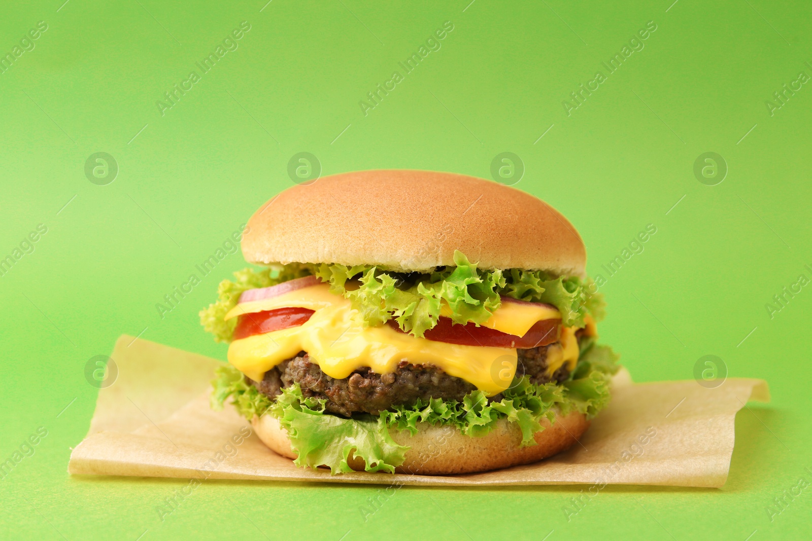 Tasty cheeseburger with sauce on green background, closeup Photo of Tasty cheeseburger with sauce on green background, closeup