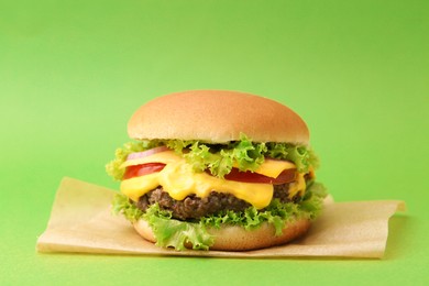 Photo of Tasty cheeseburger with sauce on green background, closeup