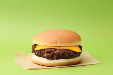 Photo of Cheeseburger with tasty patty on green background, closeup