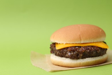 Photo of Cheeseburger with tasty patty on green background, closeup. Space for text