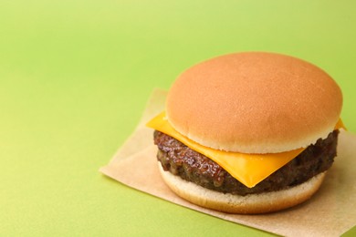 Photo of Cheeseburger with tasty patty on green background, closeup. Space for text