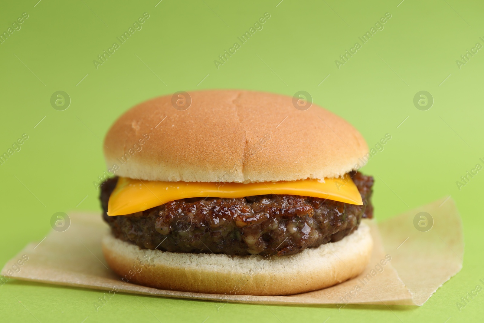 Cheeseburger with tasty patty on green background, closeup Photo of Cheeseburger with tasty patty on green background, closeup