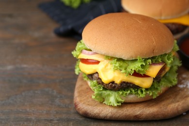 Photo of Tasty cheeseburgers on wooden table, closeup. Space for text