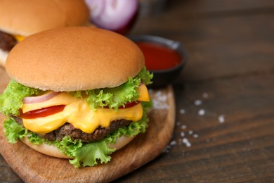 Photo of Tasty cheeseburgers on wooden table, closeup. Space for text