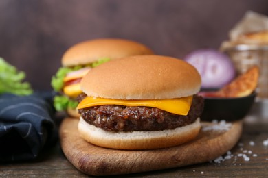Photo of Tasty cheeseburgers served on wooden table, closeup