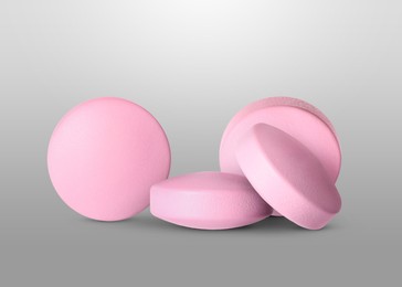 Image of Antibiotic pills. Round pink tablets on grey gradient background