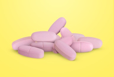Image of Antibiotic pills. Pink tablets on yellow gradient background