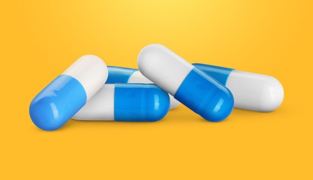 Image of Antibiotic pills. White and blue capsules on orange gradient background. Banner design