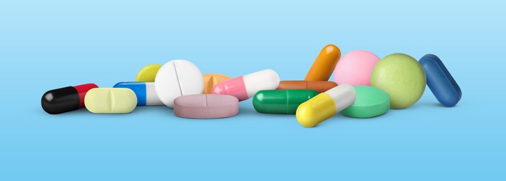 Image of Different antibiotic pills on light blue background. Banner design