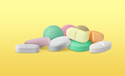 Image of Different antibiotic pills on yellow gradient background. Banner design