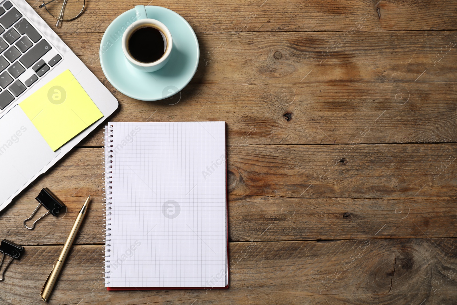 Notebook with pen, sticky note, laptop, paper clips and coffee on wooden table, flat lay. Space for text Photo of Notebook with pen, sticky note, laptop, paper clips and coffee on wooden table, flat lay. Space for text
